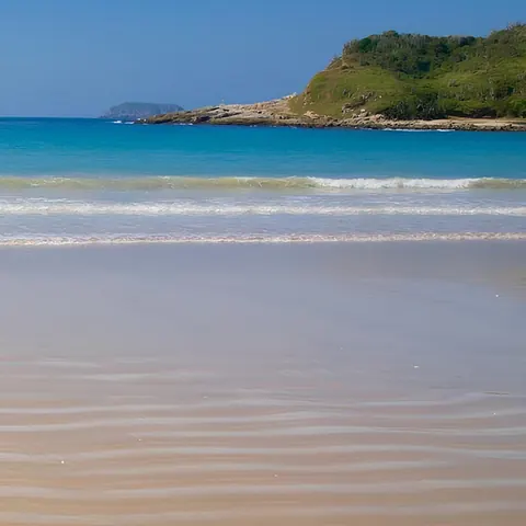 Vídeo da Luni sobre o pacote para Itapema: faixa de areia, mar azul e morro verde