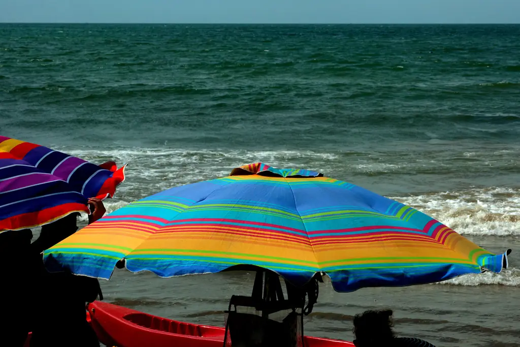 Guarda-sóis listrados em cores vivas na beira do mar da Meia Praia, em Itapema